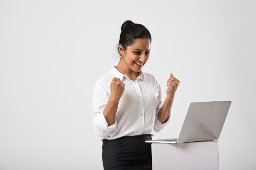 Excited businesswoman celebrating success after receiving positive news on laptop
