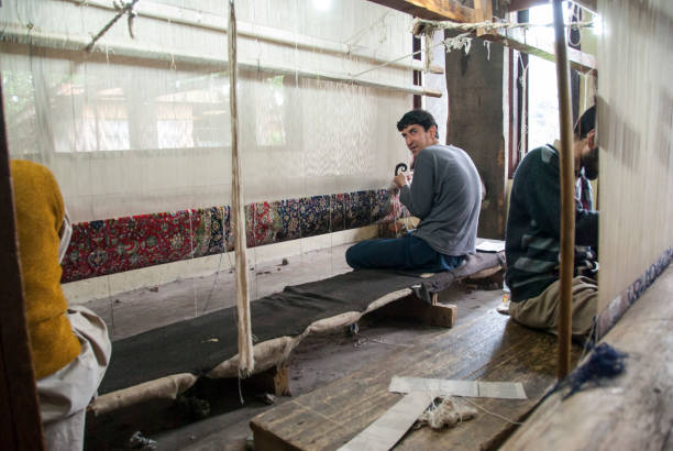 Man weaves a carpet in Srinagar, Kashmir, India. Srinagar, India - May 5th, 2009: Unidentified man weaves a carpet in Srinagar, Kashmir, India. Traditional Kashmiri handmade carpets are highly valued since ancient times. carpet factory photos stock pictures, royalty-free photos & images