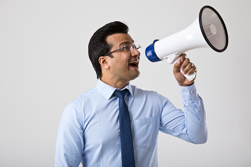 Excited businessman cheering and screaming through megaphone
