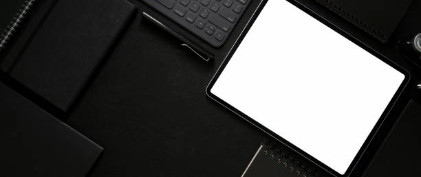 istock Top view of dark workspace with mock-up tablet, wireless device, office supplies and copy space 1214639835