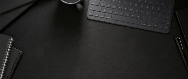 istock Top view of dark workspace with wireless device, office supplies and copy space 1214639885