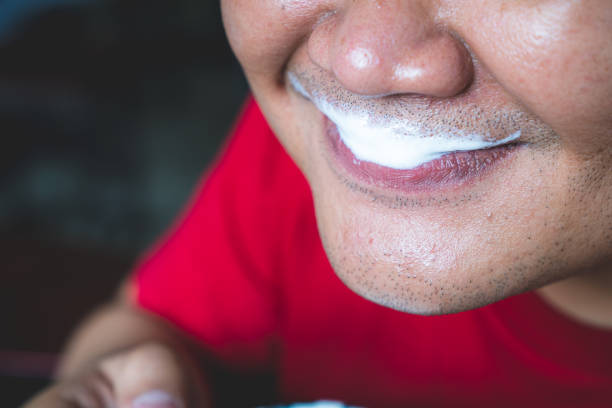 Close-up of a man's lips with milk foam attached Close-up of a man's lips with milk foam attached cappuccino coffee froth milk stock pictures, royalty-free photos & images