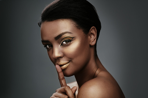 Cropped shot of a beautiful young woman wearing gold makeup against a grey background