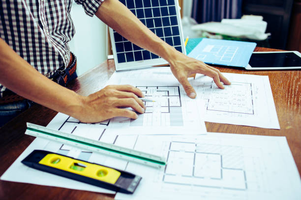istock Close-up hand of male Architect drawing blueprint on work space in construction site. 1214645008