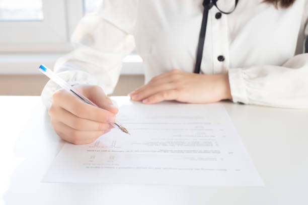istock Drawing up a tax return. Hands holding a pen for signature 1214646985