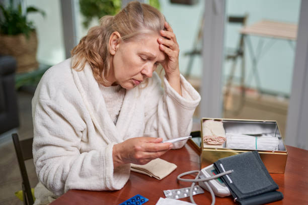 istock Sickness, seasonal virus problem concept. Senior woman being sick having flu at temperature on thermometer. 1214651422