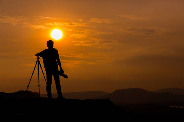 istock shooting sunset, photographer going up the hill during sunset 1214652806