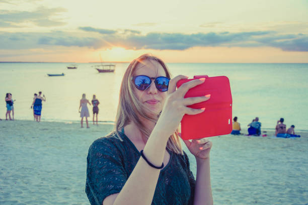 Beautiful woman taking selfie on the beach during sunset