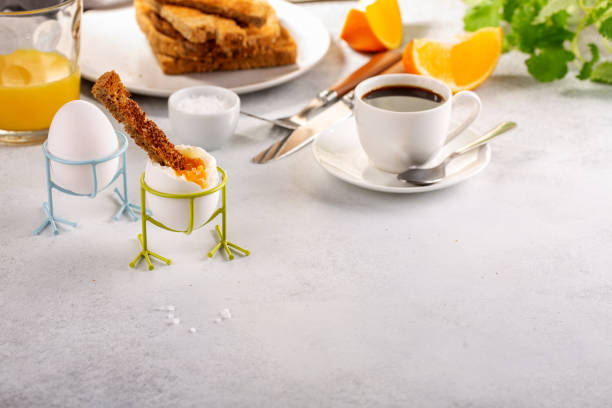 Delicious breakfast with soft boiled eggs, toasted bread, cup of coffee and orange juice.