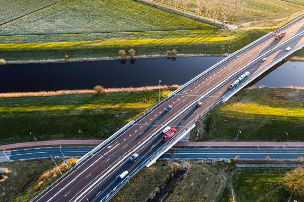 un puente viaducto cruza un canal de la autopista a59 durante el amanecer cerca de waalwijk, noord brabant, países bajos - highway traffic aerial view netherlands fotografías e imágenes de stock