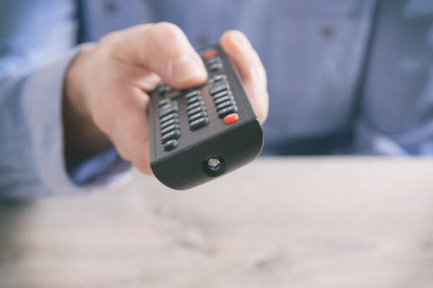 istock Man holding tv remote control and changing TV channels 1214663952
