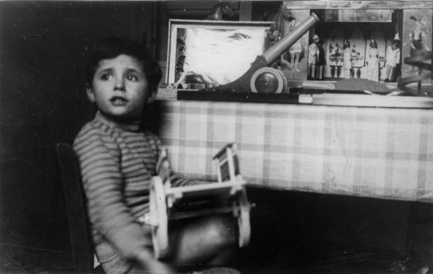 Elegant dressed boy posing against a wood furniture in his rural apartment. Ancona, Marche. 1936 Italy Elegant dressed boy posing against a wood furniture in his rural apartment. Ancona, Marche. 1936 Italy 1930s style men image created 1920s old fashioned stock pictures, royalty-free photos & images