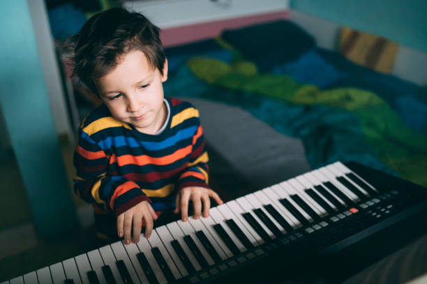 istock Happy little boy singing while playing digital piano at home 1214673330