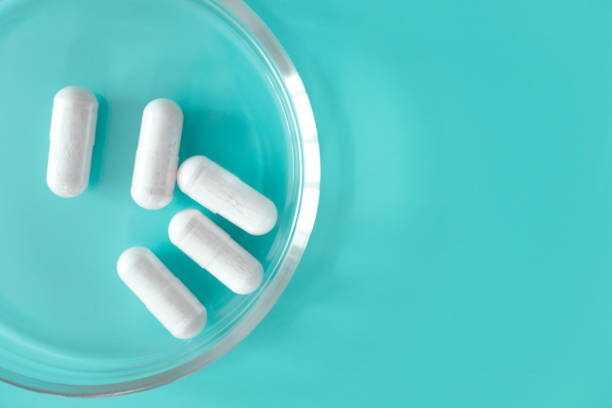 鎮痛剤、抗生物質または抗ウイルス薬は、コピースペース、トップビューと青い背景にガラスシャーレでカプセル。研究室の研究医療と医学. - pill medicine laboratory narcotic ストックフォトと画像