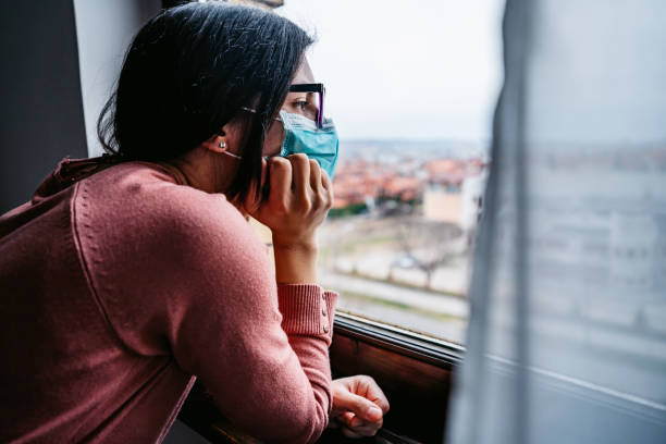 istock Woman in quarantine looking through the window 1214676337