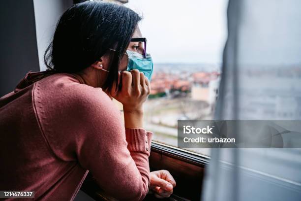 Woman In Quarantine Looking Through The Window Stock Photo - Download Image Now - Lockdown, Protective Face Mask, Recovery
