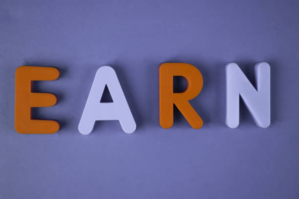 istock Earn word written with different colored letter blocks arranged on a light blue background 1214681633