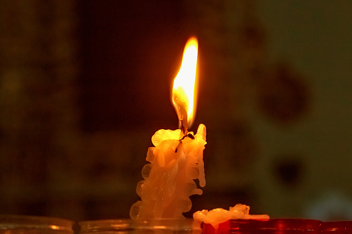 Burning candle on a dark red background
