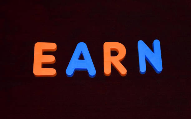 istock Earn word written with different colored letter blocks arranged on a dark background 1214681719