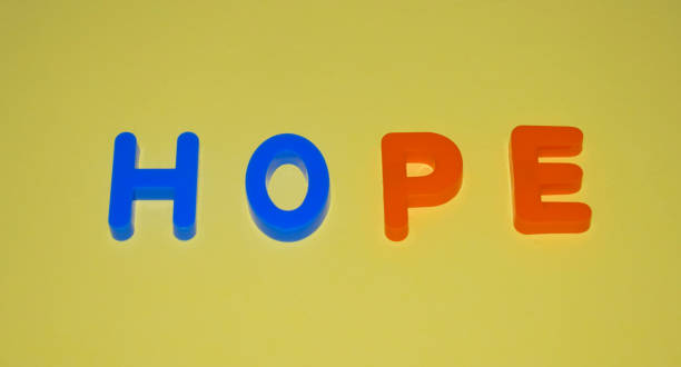 istock Hope word written with different colored letter blocks arranged on a yellow background 1214682021