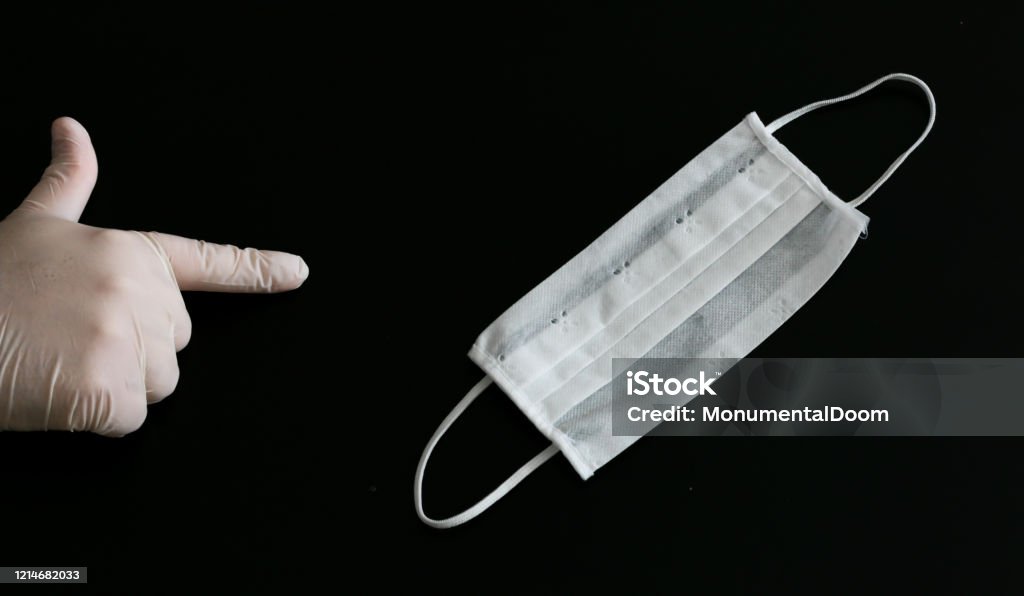 Hand in white medical glove points medical mask on black background Bulgaria Stock Photo