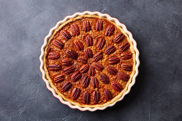 pastel de nueces, tarta en plato para hornear. postre tradicional festivo de acción de gracias. fondo oscuro. vista superior. - tart cake pie isolated fotografías e imágenes de stock