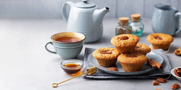 Photo of Pecan nut muffins with cup of tea on a plate. Grey background. Copy space.