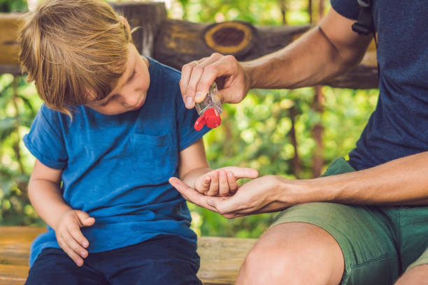 Father and son using wash hand sanitizer gel in the park before a snack Father and son using wash hand sanitizer gel in the park before a snack. antiseptic stock pictures, royalty-free photos & images