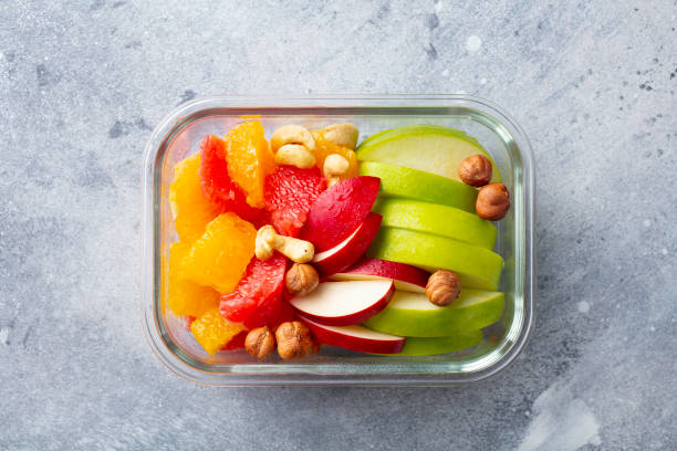 fruits salad and nuts in a glass container. healthy eating. grey background. top view. - lunch box lunch red apple imagens e fotografias de stock