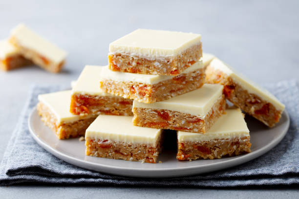 hafer, kokosnuss, aprikosenriegel mit weißer schokolade auf einem teller. grauer hintergrund. nahaufnahme. - shortbread caramel chocolate candy biscuit stock-fotos und bilder