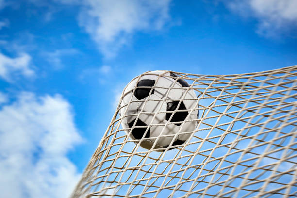 pallone da calcio in una rete e un cielo blu - foto stock