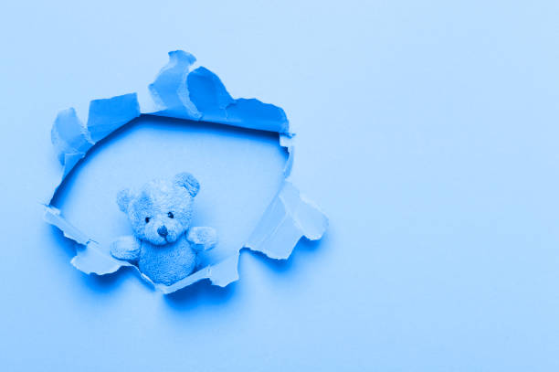 istock Teddy Bear In Paper cut hole. World Autism Awareness. Blue filter 1214687576