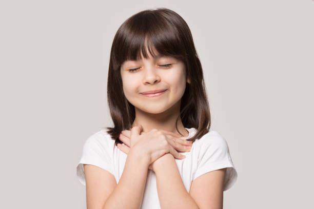 istock Cute little girl with hands on chest praying 1214694457