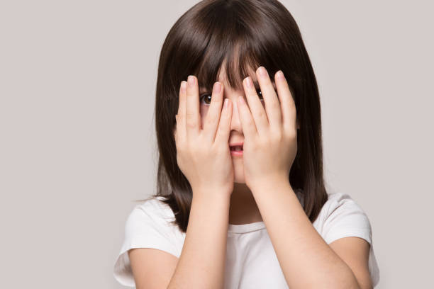 istock Scared little girl feel interested peep through fingers 1214694480