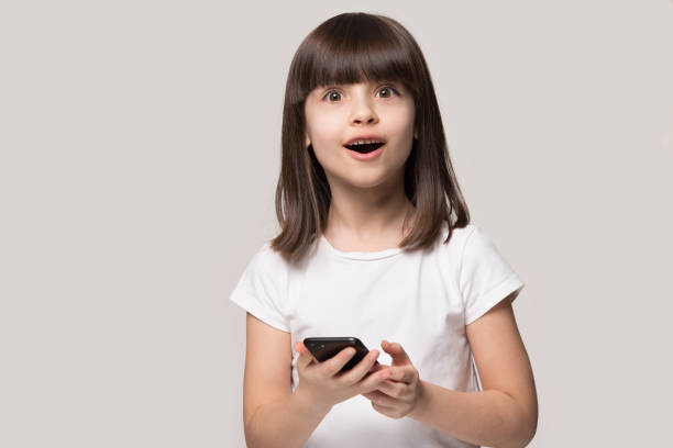 surprised little girl shocked by smartphone online application - surprise child little girls shock imagens e fotografias de stock