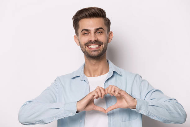 istock Smiling man look at camera showing heart with hands 1214694501