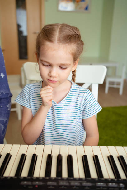 istock a little girl learns to play the synthesizer. 1214697245