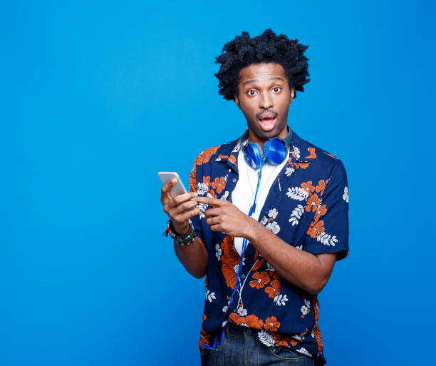 istock Surprised man in hawaiian shirt using smart phone 1214697279