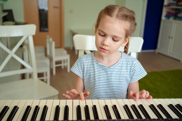 istock a little girl learns to play the synthesizer. 1214697283
