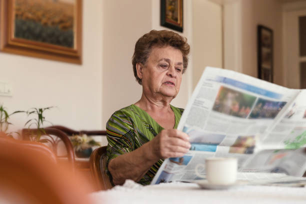 istock Serious elderly woman reading newspapers 1214698868