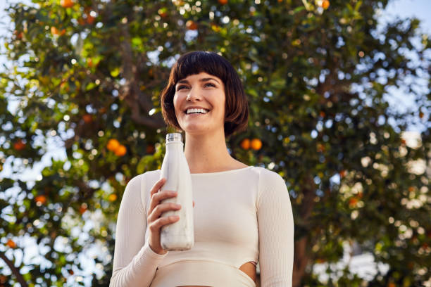 Laughing woman drinking water bottle after an outdoor exercise session