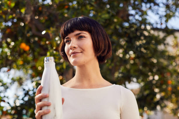 istock Smiling woman drinking water bottle after an outdoor exercise session 1214699147