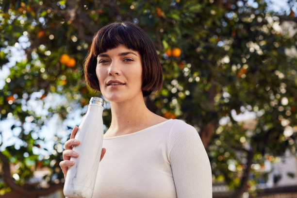 istock Young woman drinking water outside in her yard after exercising 1214699669