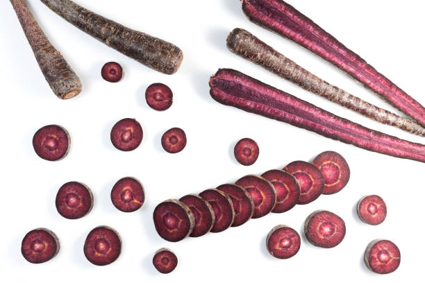 Unusual root vegetables. Purple carrots on light background. Vegetables whole and chopped. Copy space.