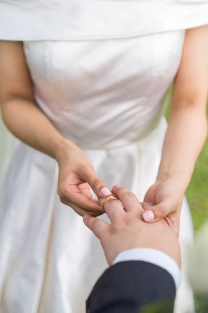 istock Bridegroom putting on the wedding ring for the bride 1214700957
