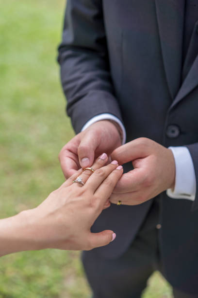 istock Bridegroom putting on the wedding ring for the bride 1214700959