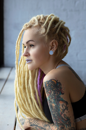 romance tattoos punk girl dreadlocks concept freedom fashion style bright personality charisma hairstyle rasta red nails manicure piercing natural light good mood