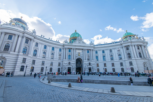 People walking in the Michaelerplatz right in front of the entrance to St. Michael´s Wing, part of the Hofburg Imperial Palace at Vienna, Austria.
