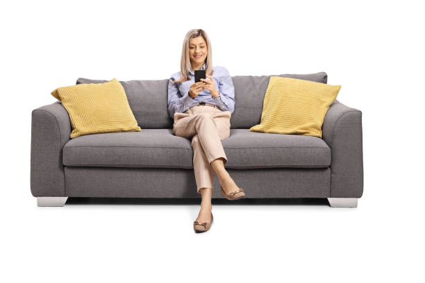 istock Woman resting on a sofa and holding a mobile phone 1214710884