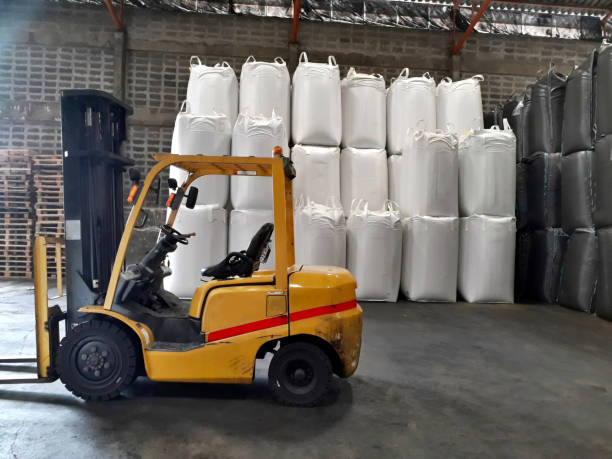 Big yellow car and chemical fertilizer Big yellow car loader and White hemp sacks containing chemical fertilizer in the warehouse. silo bag stock pictures, royalty-free photos & images